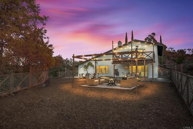 back house at dusk featuring a balcony, an outdoor living space, and a patio