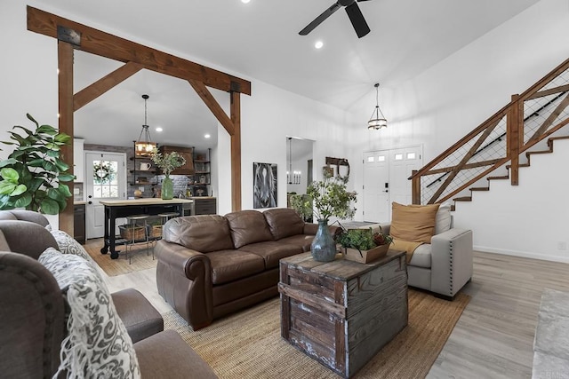 living room featuring ceiling fan with notable chandelier, high vaulted ceiling, beamed ceiling, and light wood-type flooring