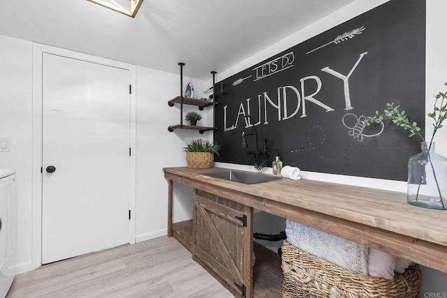 office area with light hardwood / wood-style floors, sink, and washer / clothes dryer