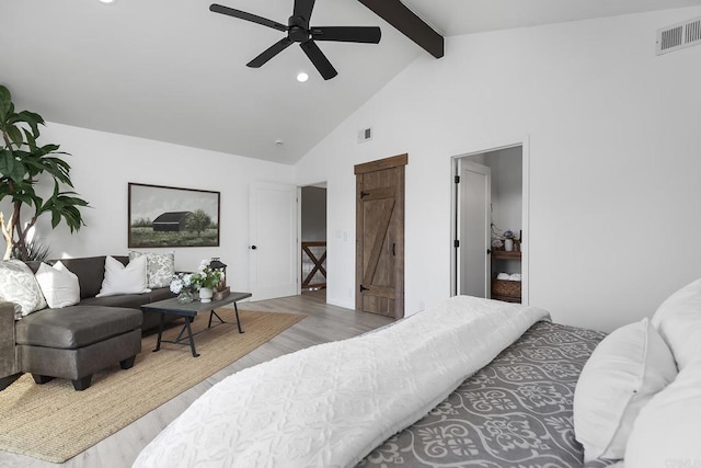 bedroom with ceiling fan, a barn door, light hardwood / wood-style floors, beam ceiling, and high vaulted ceiling