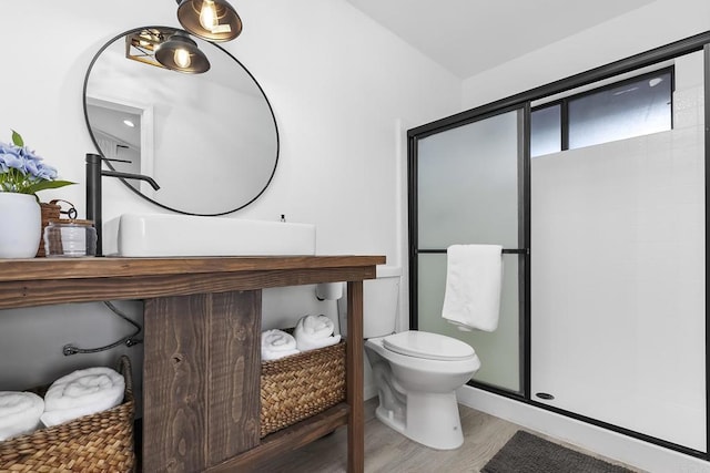 bathroom with a shower with shower door, hardwood / wood-style floors, and toilet