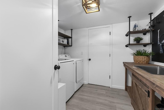 laundry area with light hardwood / wood-style floors and washing machine and clothes dryer