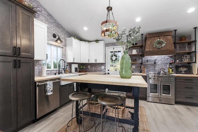 kitchen featuring appliances with stainless steel finishes, wooden counters, white cabinetry, and pendant lighting