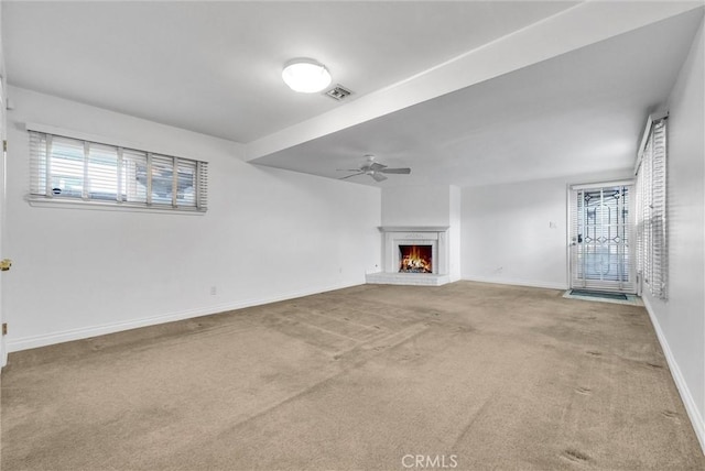 unfurnished living room with ceiling fan, a brick fireplace, and carpet