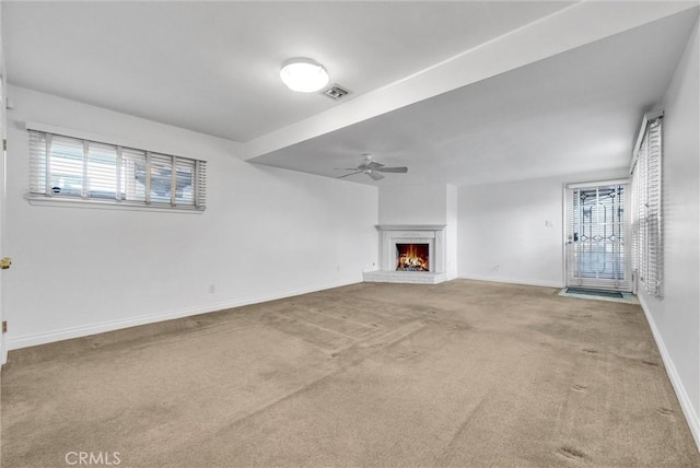 unfurnished living room featuring a ceiling fan, visible vents, carpet floors, baseboards, and a fireplace