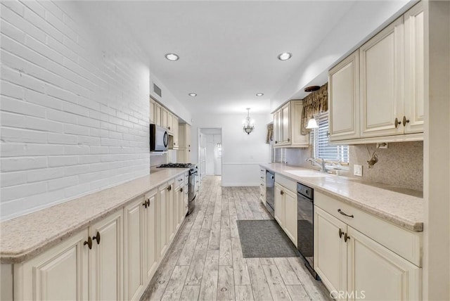 kitchen with decorative light fixtures, tasteful backsplash, sink, stainless steel appliances, and light wood-type flooring