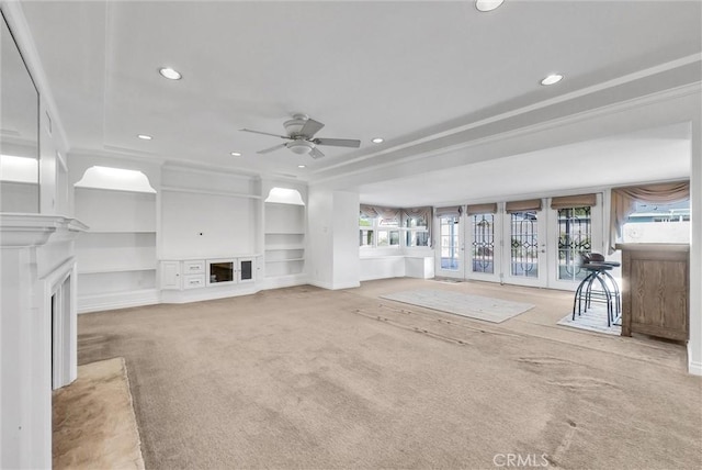 unfurnished living room featuring built in shelves, carpet floors, and ceiling fan