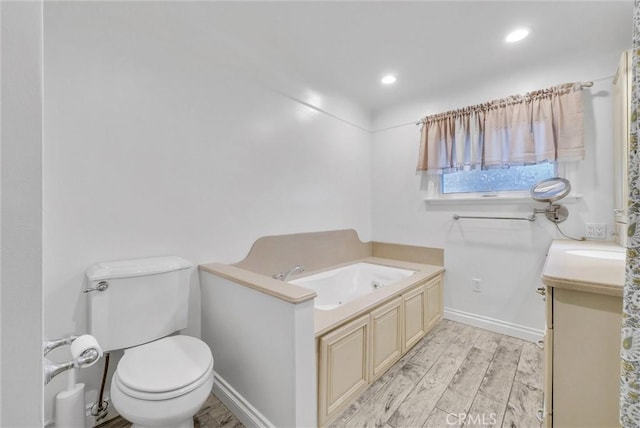 bathroom with vanity, wood finished floors, baseboards, toilet, and a bath