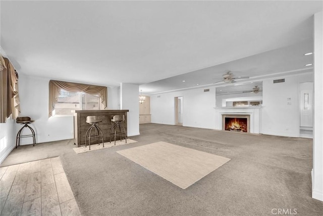 unfurnished living room featuring ceiling fan and carpet floors