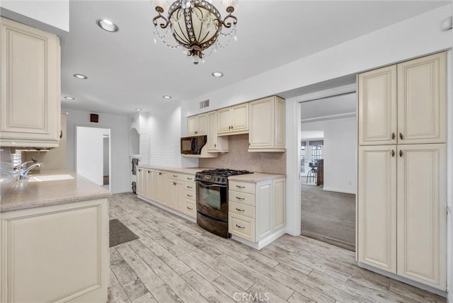 kitchen featuring tasteful backsplash, sink, black appliances, light wood-type flooring, and cream cabinetry