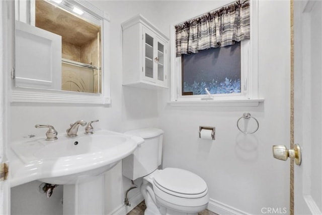 full bathroom with baseboards, toilet, walk in shower, and a sink