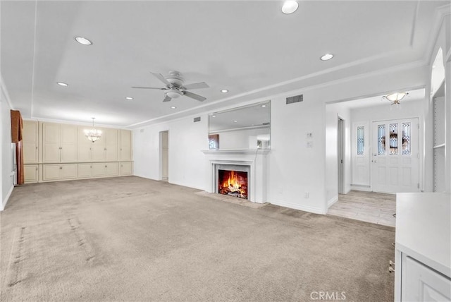 unfurnished living room with visible vents, light carpet, ceiling fan with notable chandelier, a warm lit fireplace, and recessed lighting