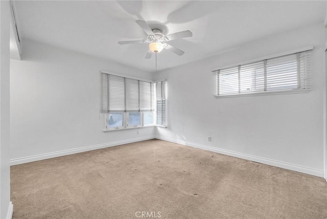 empty room featuring carpet flooring, a ceiling fan, and baseboards