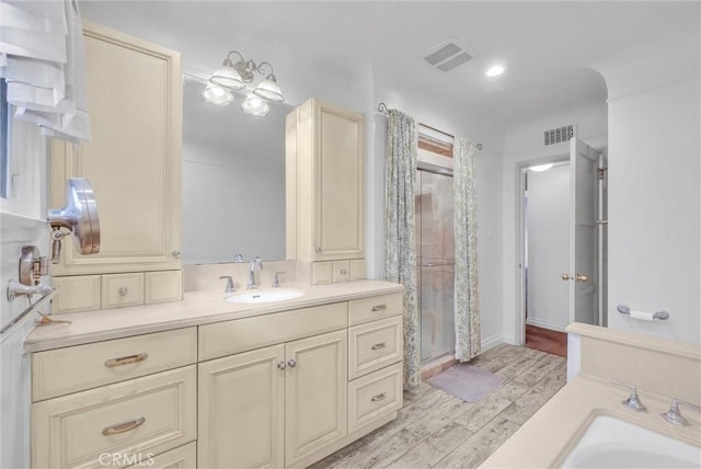 bathroom featuring hardwood / wood-style flooring, vanity, and walk in shower