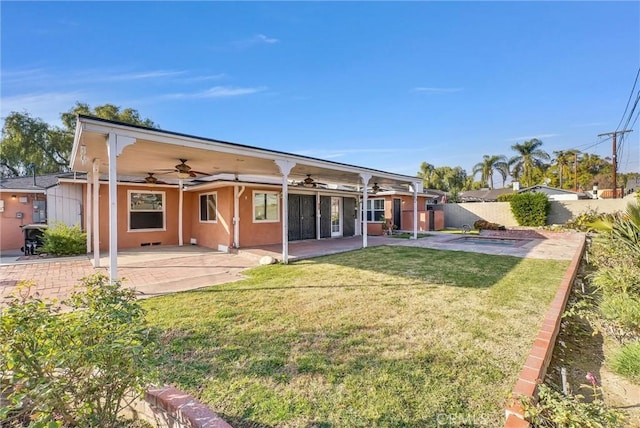 rear view of property featuring fence, stucco siding, a yard, a patio area, and a ceiling fan