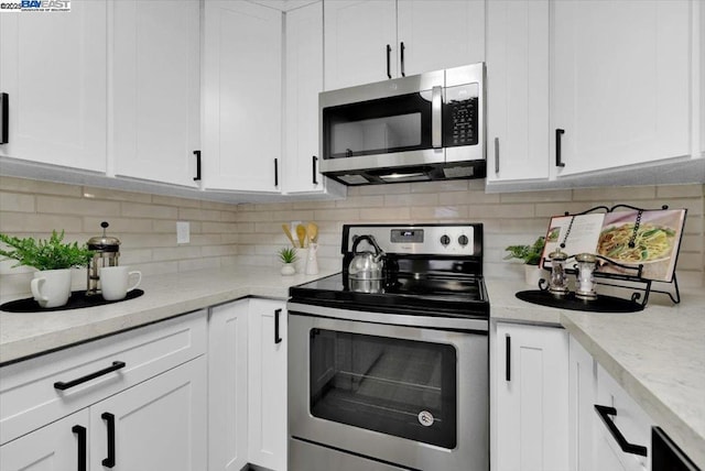 kitchen with white cabinetry, stainless steel appliances, and tasteful backsplash