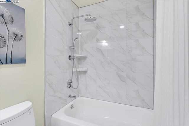 bathroom featuring toilet and tiled shower / bath