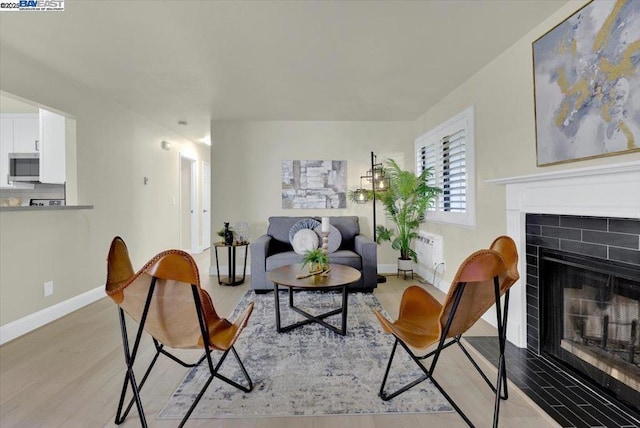 sitting room featuring light wood-type flooring and a brick fireplace