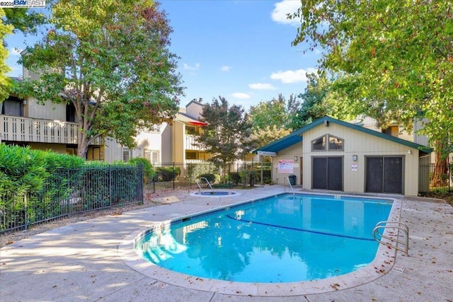 view of pool with a patio area, a hot tub, and an outdoor structure