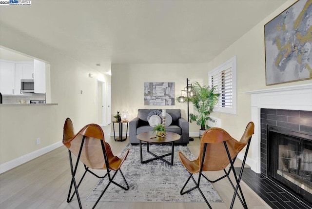 living room featuring light wood-type flooring and a brick fireplace