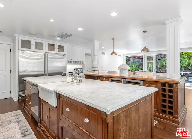 kitchen with white cabinets, appliances with stainless steel finishes, an island with sink, and pendant lighting