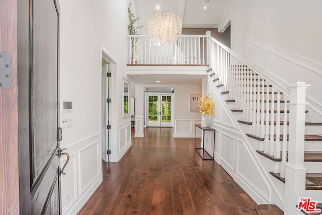 entryway featuring dark wood-type flooring, a high ceiling, and a notable chandelier