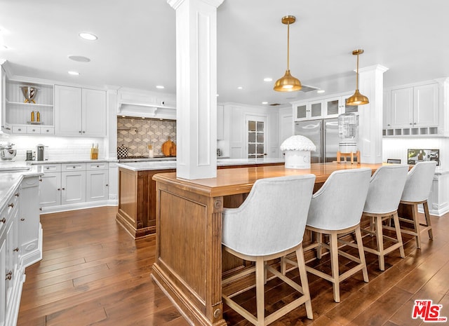 kitchen with white cabinetry, dark hardwood / wood-style floors, decorative light fixtures, built in fridge, and a center island