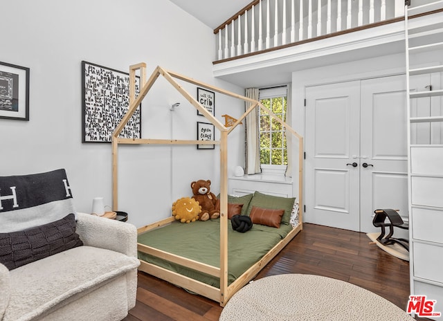 bedroom featuring a closet, dark hardwood / wood-style floors, and a towering ceiling