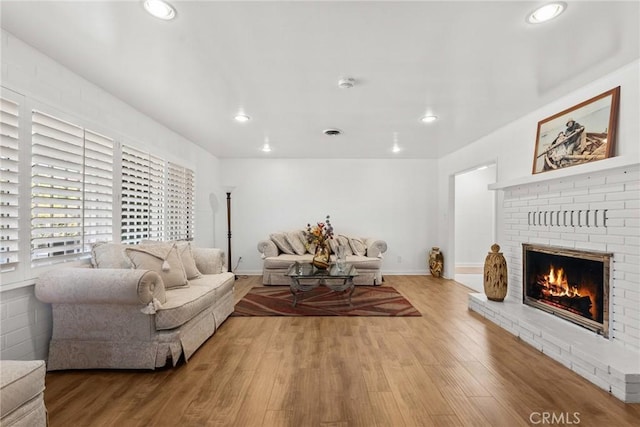 living room with a brick fireplace and hardwood / wood-style floors