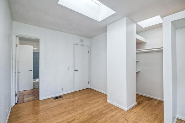 unfurnished bedroom featuring light wood-type flooring, a closet, and a skylight