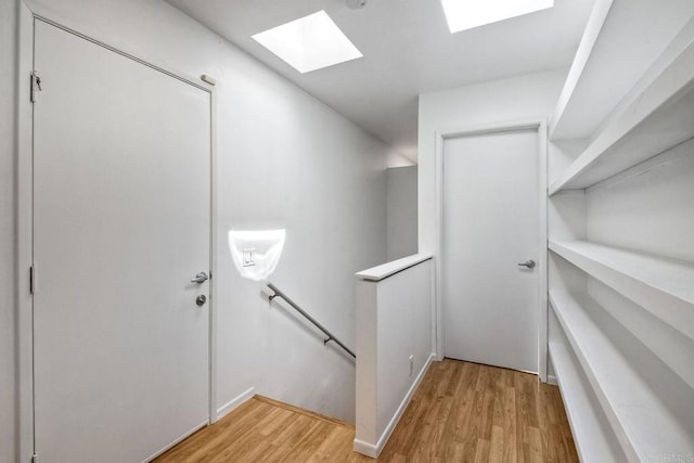 stairs with a skylight and hardwood / wood-style flooring