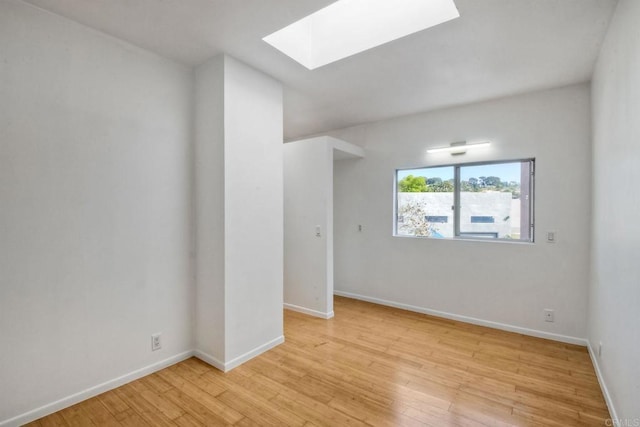 spare room featuring light hardwood / wood-style flooring and a skylight