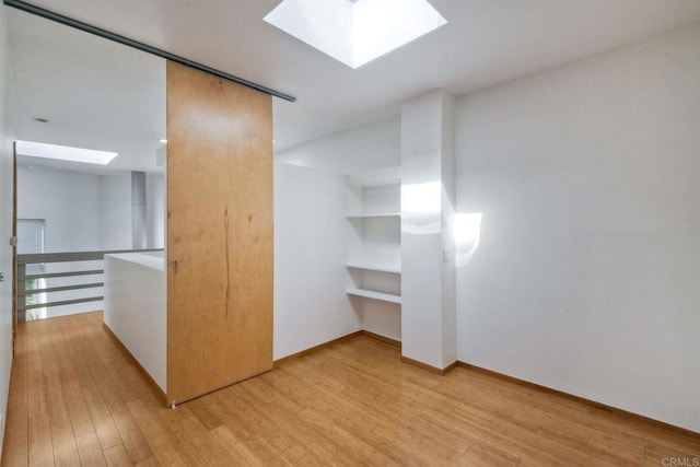 interior space featuring a skylight and light hardwood / wood-style flooring