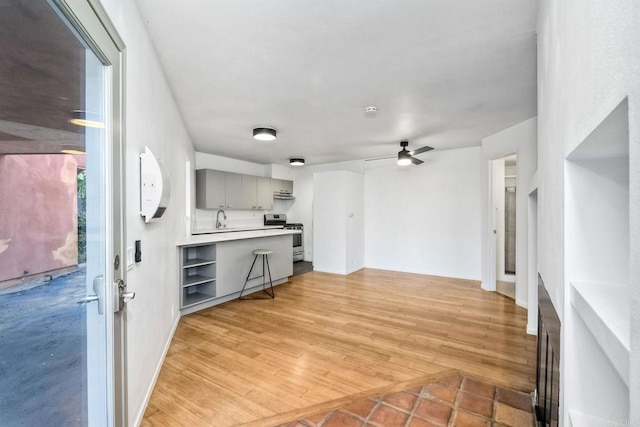 unfurnished living room featuring ceiling fan, sink, and light hardwood / wood-style flooring