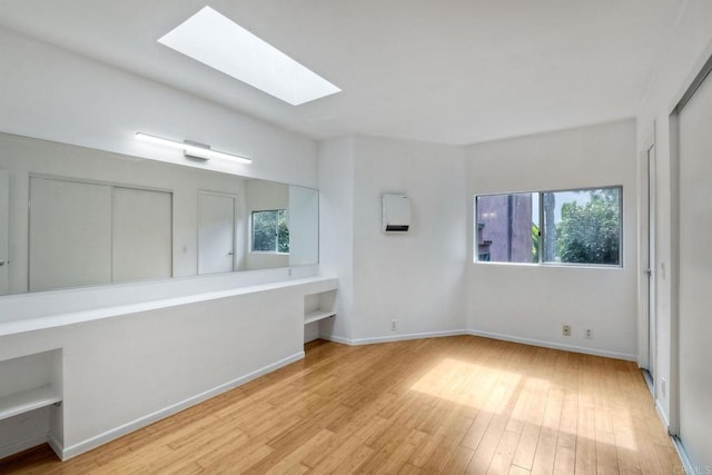 unfurnished bedroom featuring light hardwood / wood-style floors and a skylight