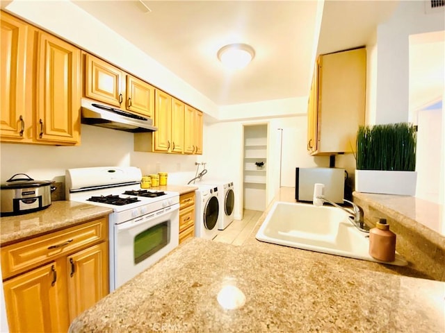 kitchen with washer and dryer, sink, white range with gas stovetop, and light stone countertops