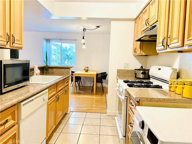 kitchen featuring white appliances, light brown cabinetry, sink, hanging light fixtures, and light tile patterned flooring