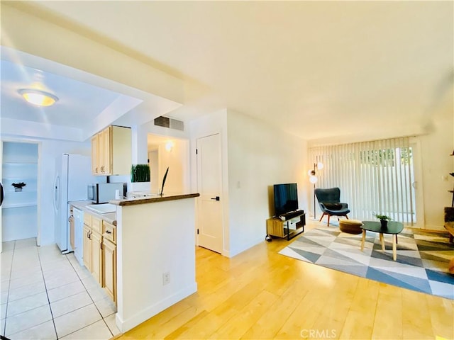 kitchen featuring light hardwood / wood-style floors, light brown cabinets, and white appliances