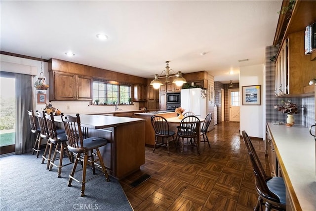 kitchen with black appliances, a center island, decorative light fixtures, dark parquet floors, and a breakfast bar area