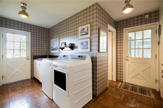 laundry area with washer and clothes dryer, sink, dark parquet flooring, and cabinets