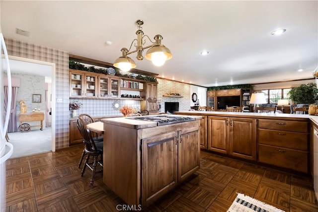 kitchen with a kitchen island, kitchen peninsula, a kitchen bar, hanging light fixtures, and stainless steel gas cooktop