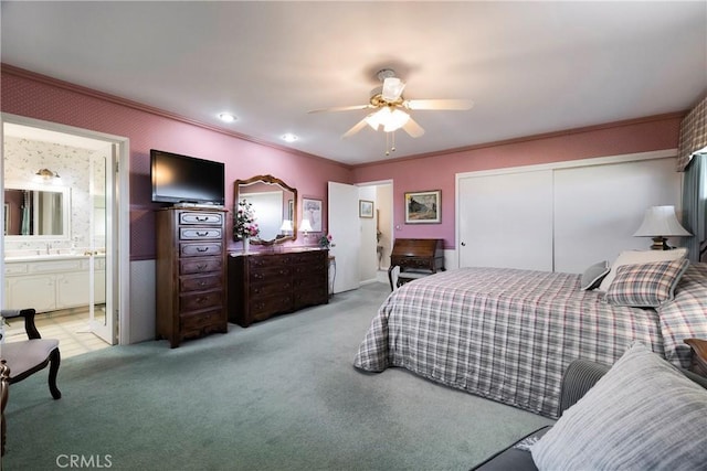 carpeted bedroom with sink, a closet, ceiling fan, ensuite bathroom, and crown molding