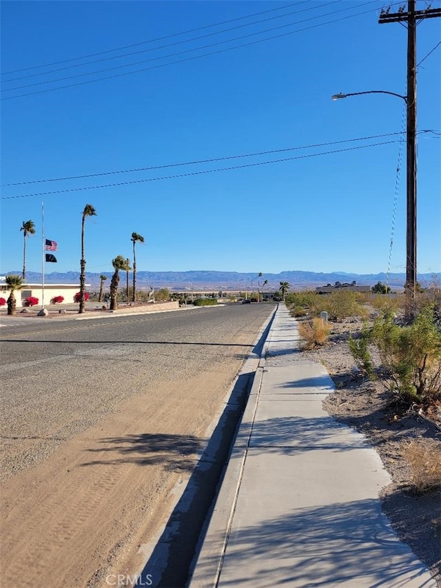1217 Lill Hill Dr, Needles, CA 92363 - view of asphalt road with curbs, a mountain view, and street lights
