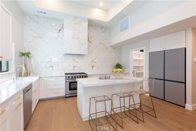 kitchen with white cabinetry, appliances with stainless steel finishes, tasteful backsplash, a kitchen breakfast bar, and a kitchen island