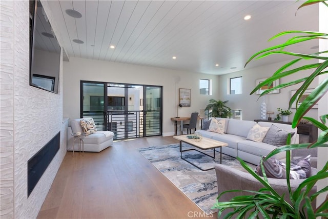 living room with wood ceiling, wood-type flooring, and a stone fireplace