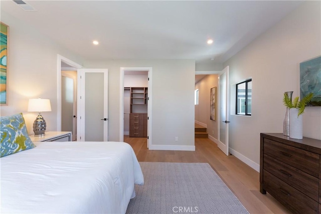 bedroom with a spacious closet, light hardwood / wood-style floors, and a closet