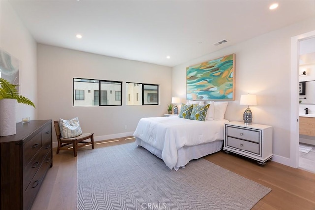 bedroom featuring hardwood / wood-style flooring and ensuite bath