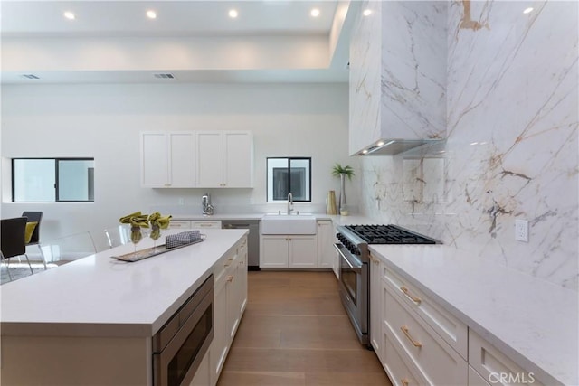 kitchen featuring backsplash, a kitchen island, sink, stainless steel appliances, and white cabinets