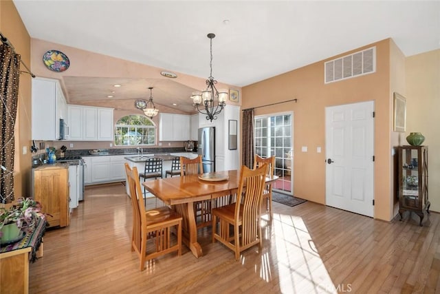 dining area featuring light hardwood / wood-style floors, a chandelier, and vaulted ceiling