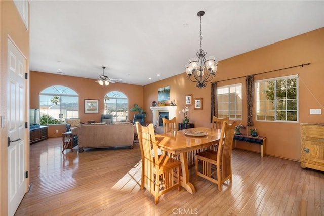 dining area with ceiling fan with notable chandelier and light hardwood / wood-style floors